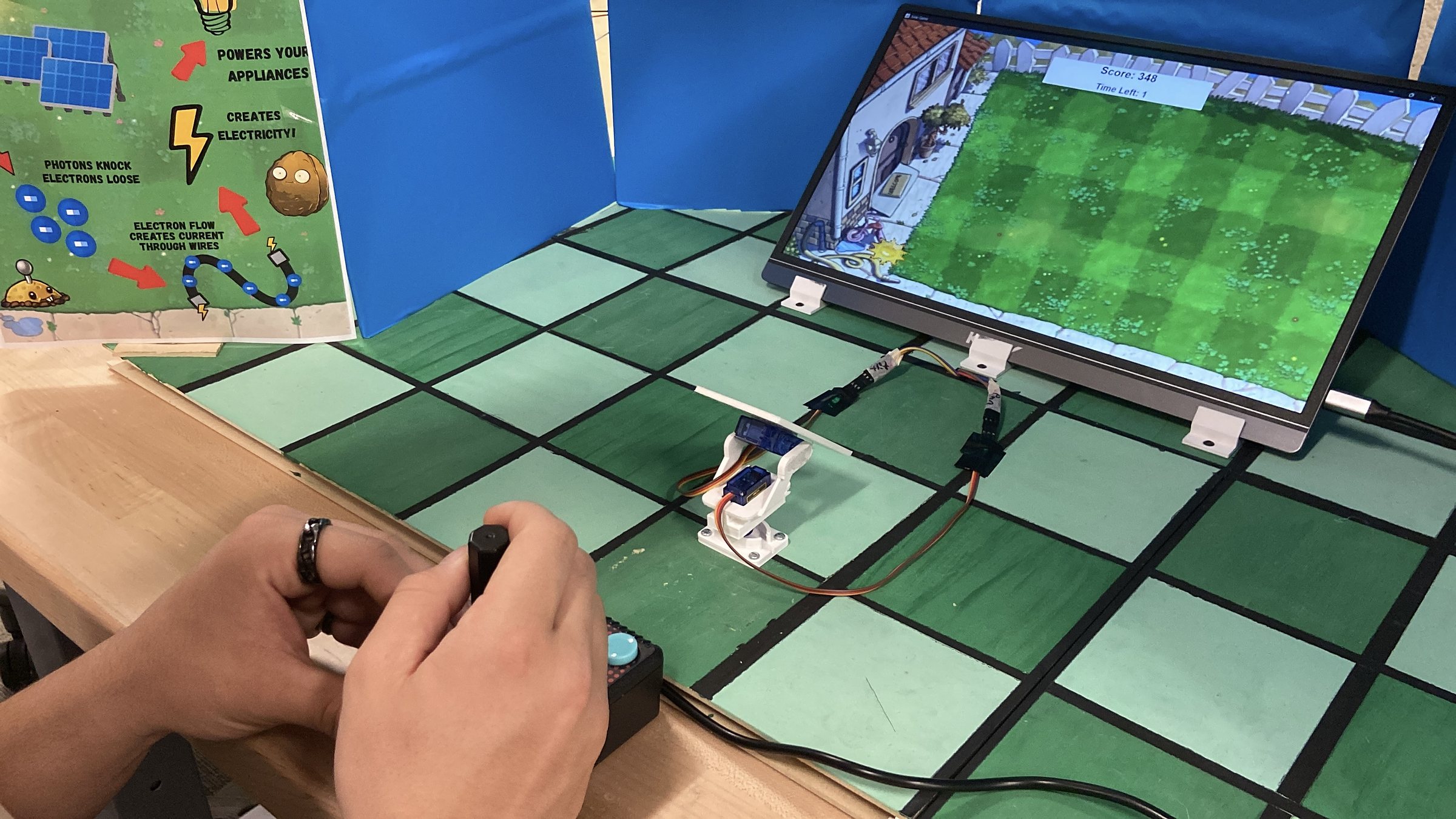A player aims the 3D-printed sunflower panel with the arcade joystick on the finished Solar Tracker Arcade exhibit